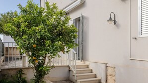 Un bâtiment avec un escalier, un arbre portant des fruits et un luminaire fixé au mur.