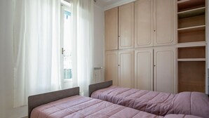 Une chambre avec deux lits, une armoire et une fenêtre avec des rideaux.