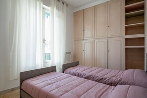 Een slaapkamer met twee bedden, een kledingkast en een raam met gordijnen.