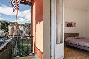 Un balcon donnant sur la ville, un lit avec un matelas et un tableau accroché au mur.