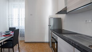 Une cuisine moderne équipée d’un réfrigérateur en acier inoxydable, d’une cuisinière et d’un plan de travail noir.