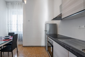 Una cocina moderna con un refrigerador de acero inoxidable, una estufa y una encimera negra.