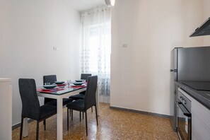 Una cocina compacta con una mesa, sillas y horno empotrado.
