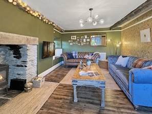 A cozy living room with a stone fireplace, a wooden coffee table, and a blue sofa.