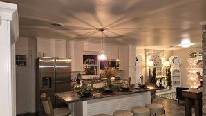 Une cuisine moderne dotée d’un îlot central, d’appareils électroménagers en acier inoxydable et d’un lustre.