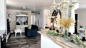 Un salon moderne avec un parquet en bois foncé, un canapé bleu, une cheminée blanche et un lustre.