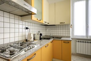 Una cocina con estufa a gas, hervidor, tostadora y pileta.