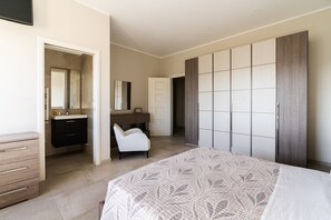A bedroom with a bed, a wardrobe, a desk, and a chair.