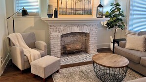 A living room with a fireplace, a sofa, a chair, a coffee table, and a floor lamp.