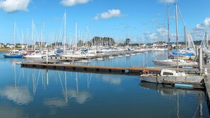 Een jachthaven met diverse zeilboten afgemeerd bij houten steigers.
