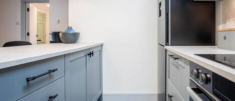 A modern kitchen with grey cabinets, a black refrigerator, and a built-in oven.
