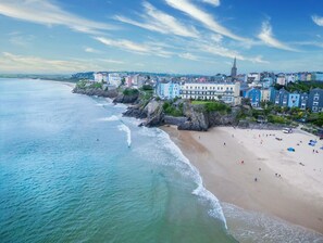 A coastal town with a beach, buildings, and a prominent church spire. - Sandy Steps - 1 Bedroom Apartment - Tenby (Tenby)