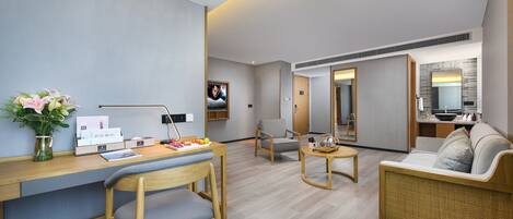 A modern hotel room with a wooden desk, a comfortable sofa, a small round table, and a TV.