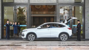 Un SUV blanco estacionado frente a un edificio con entrada de vidrio y un cartel que dice "Lindsey".