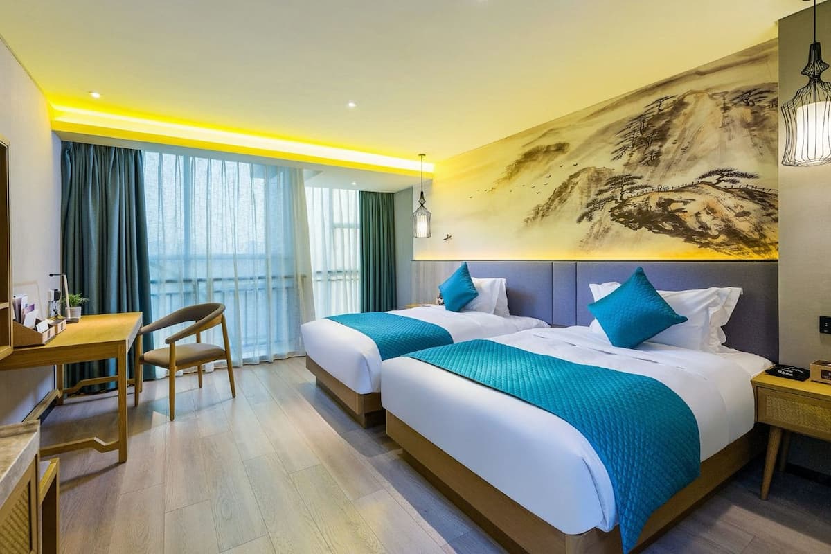 Quarto de hotel com duas camas, uma escrivaninha e uma cadeira.