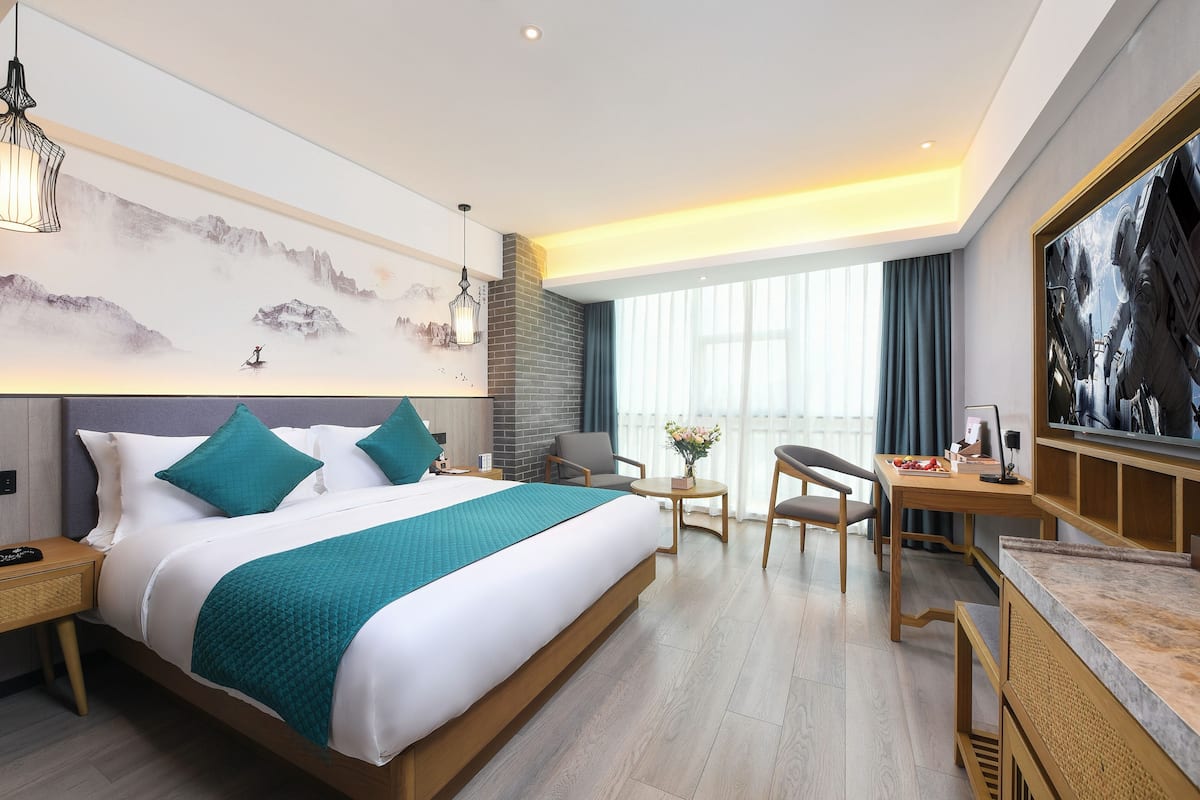 Quarto de hotel moderno com uma cama grande, uma escrivaninha e uma televisão.
