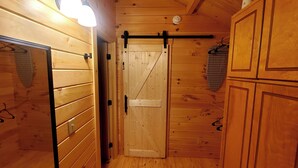 Un interior de madera con una puerta corredera, un perchero colgante y una lámpara en el techo.