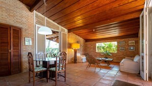 Un vaste espace dédié à la salle à manger, avec un mur en briques, un plafond en bois et une vue sur la verdure environnante.