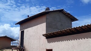Ein kleines Gebäude mit Ziegeldach, einer Treppe, die zu einer Tür führt, und einem abgestellten Motorrad.