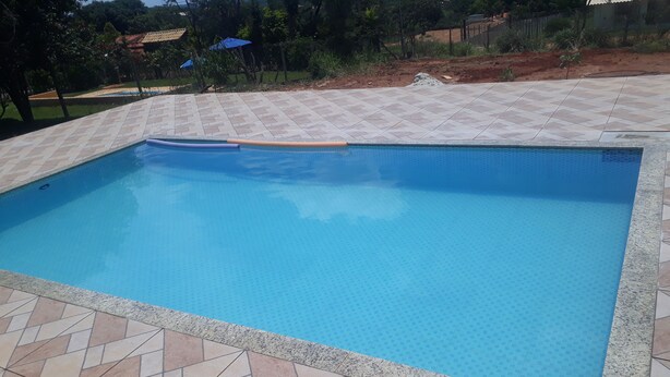 Ein rechteckiger Pool mit einer bepflasterten Kante und einer ihn umgebenden, gefliesten Terrasse.