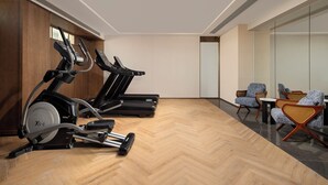 A gym with two elliptical machines, wooden flooring, and a seating area with chairs. - Mehood Lestie International Hotel Panyu Flagship Branch - Free Shuttle Bus to Canton Fair Complex During Canton Fair Period (Guangzhou)