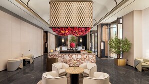 A modern lobby with a marble reception desk, a large hanging floral arrangement, and comfortable seating areas. - Mehood Lestie International Hotel Panyu Flagship Branch - Free Shuttle Bus to Canton Fair Complex During Canton Fair Period (Guangzhou)