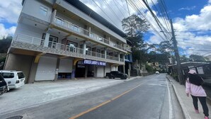 A two-story building with a sign for 'HYDROED LAUNDRY & FOOD HOUSE' on the ground floor. There are cars parked in front, and a person is walking on the sidewalk. - Good Living Baguio (Baguio)