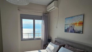 Un dormitorio con cama, ventana con vista al mar, aire acondicionado y un cuadro en la pared.