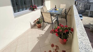Un balcon avec une table et des chaises, des plantes en pot et une vue sur la ville.