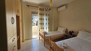 Une chambre avec deux lits simples, une armoire, un ventilateur de plafond et un appareil de climatisation.