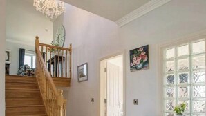 Eine Holztreppe führt zu einer Zwischenebene mit einem Chandelier, einer Tür und einem Fenster mit Blick.
