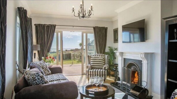 Ein geräumiges Wohnzimmer mit Kamin, einer Sofagarnitur und Blick ins Freie.
