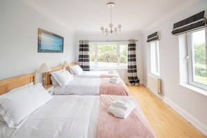 A hotel room with two beds, a painting, a window with curtains, and a radiator.