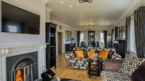 Ein Wohnzimmer mit Kamin, einer Sofagarnitur, einem Esstisch und einer Chandelier.