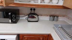 Une cuisine équipée d’un four à micro-ondes, d’un grille-pain et de placards contenant de la vaisselle.