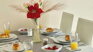 A breakfast setting with croissants, strawberries, orange juice, and a vase with flowers. - Cosy Home-Sleeps 5- Private Garden- Free Parking (Corby)