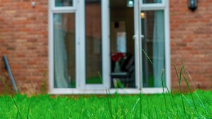 A brick building with a glass door and windows. - Cosy Home-Sleeps 5- Private Garden- Free Parking (Corby)