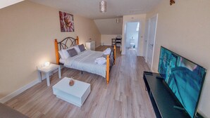 A bedroom with a bed, bedside tables, a TV, and a painting on the wall. - Cosy Home-Sleeps 5- Private Garden- Free Parking (Corby)