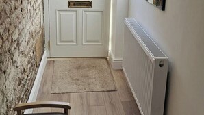 A hallway with a white door, a radiator, and a rug on the floor. - Stylish 2-Bed House in Stamford Town Centre (Stamford)