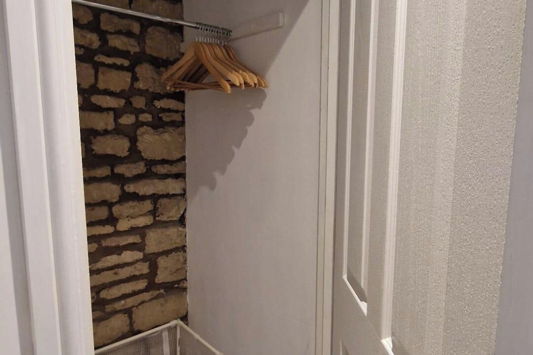 Un pasillo estrecho con una pared de piedra a un lado y una puerta blanca al otro.