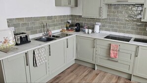 A kitchen with light-colored cabinets, a sink, a toaster, a kettle, and a coffee maker. - Stylish 2-Bed House in Stamford Town Centre (Stamford)