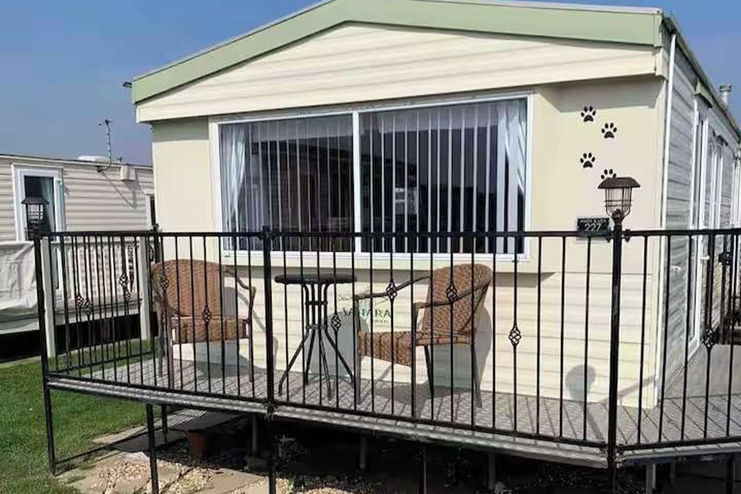 A mobile home with a covered patio area, a small table, and two chairs.
