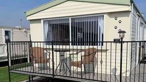 A mobile home with a covered patio area, a small table, and two chairs. - 2Bed Caravan Sleeps 6- Beach Access, Pets, Parking (Mablethorpe)