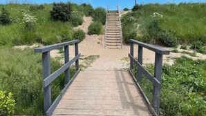 A wooden pathway leading to a staircase surrounded by greenery. - 2Bed Caravan Sleeps 6- Beach Access, Pets, Parking (Mablethorpe)