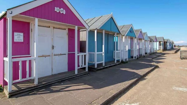 A row of beach huts with white railings and doors, painted in various colors. - 2Bed Caravan Sleeps 6- Beach Access, Pets, Parking (Mablethorpe)