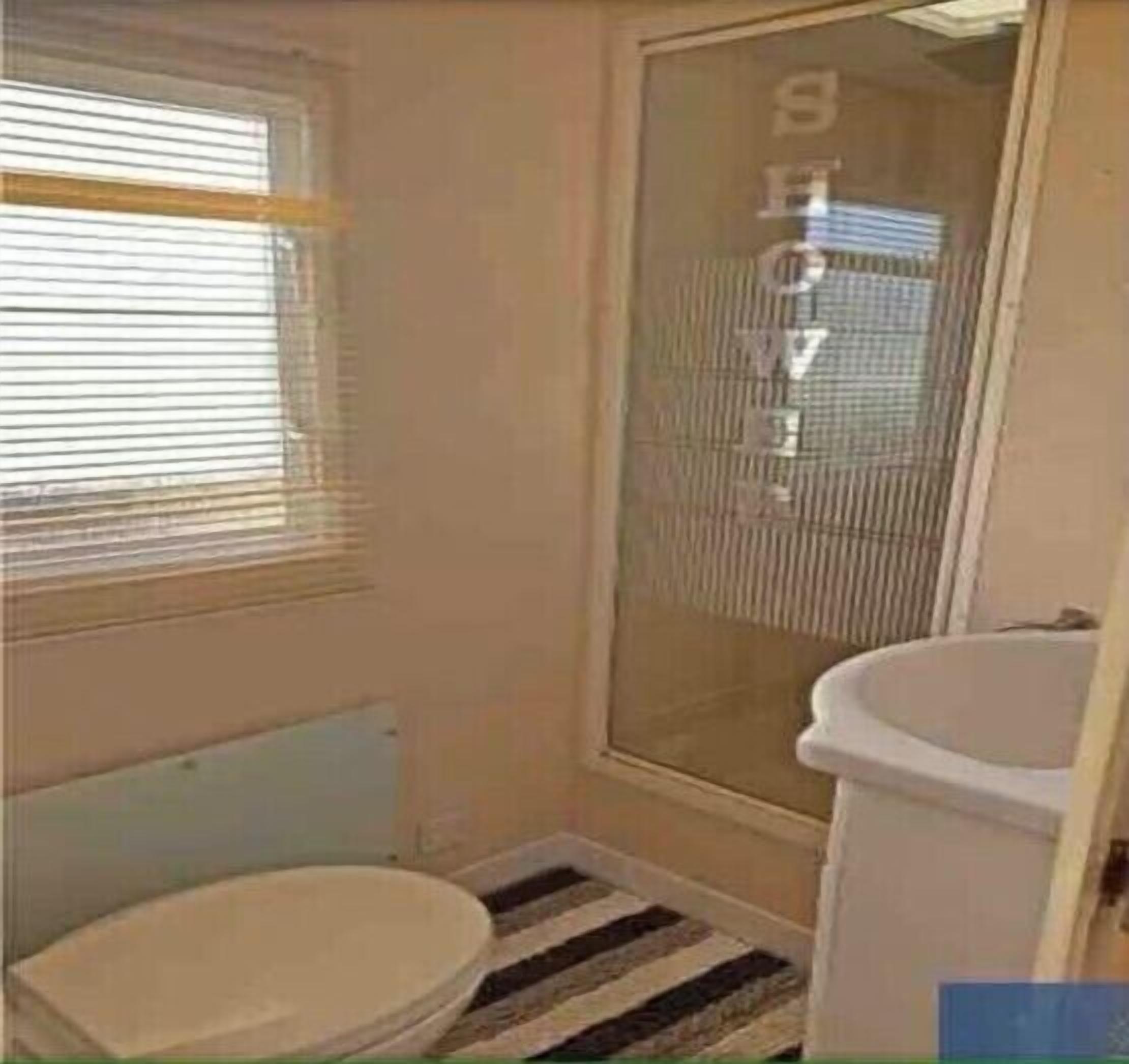 A small bathroom with a toilet, a sink, and a shower.