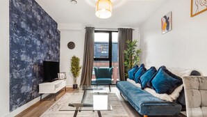 Ein modernes Wohnzimmer mit einer Couch, einem Fernseher und einem Glastisch.