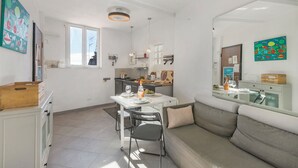 A modern kitchen with white cabinets, a dining table with chairs, and a large window. - Un Terrazzo Nella Pigna, Sea-View Terrace, Sanremo, Italy (Sanremo)