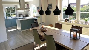 Een moderne keuken met een eethoek, een groot raam en uitzicht op groen.