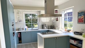 Een moderne keuken met een centraal eiland, inbouwmeubels en een raam dat voor natuurlijk licht zorgt.